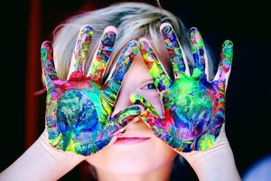 Child playing with coloured paints on hand