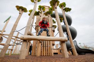 child standing atop a wooden play frame