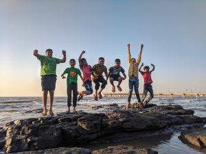 Kids jumping on a rock in the sea