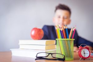 School boy with books, apple, pencils, glasses, and alarm clock