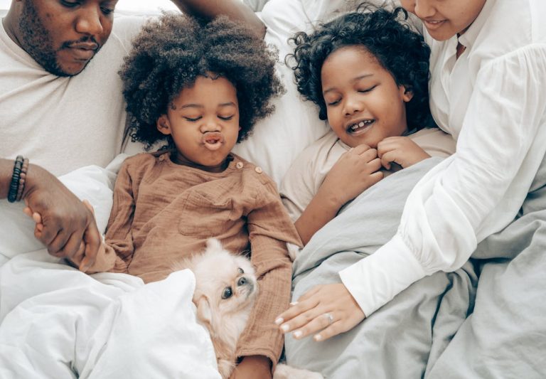 Family lying in bed with dog talking about affirmations