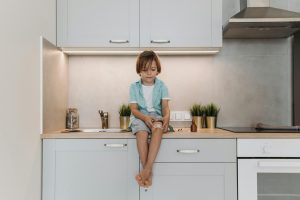 child with plaster on knee sitting on counter top