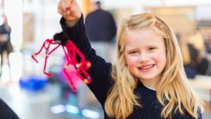 Girl holding up spider made out of pipe cleaners for Halloween