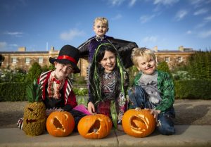 Children dressed up for Halloween with pumpkins standing infront of Hillsborough Castle Gardens