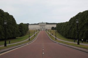 Red tarmac road, lined with trees leading to Northern Ireland's parliament buildings