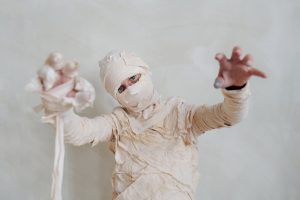 Child dressed up as a mummy with hands in the air