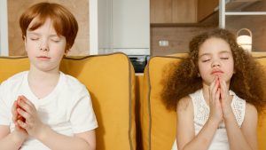 two children sat on sofa meditating