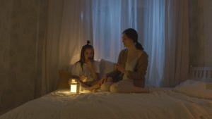 mother and daughter sharing snack in bed and talking