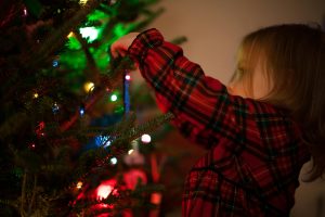 child hanging decorations on a christmas tree