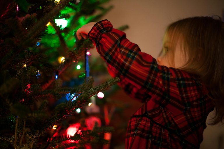 child hanging decorations on a christmas tree