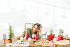 Woman looking stressed, playing with hair, sitting at table dressed for Christmas