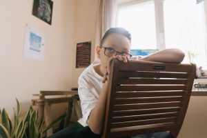 child hanging on back of chair looking bored